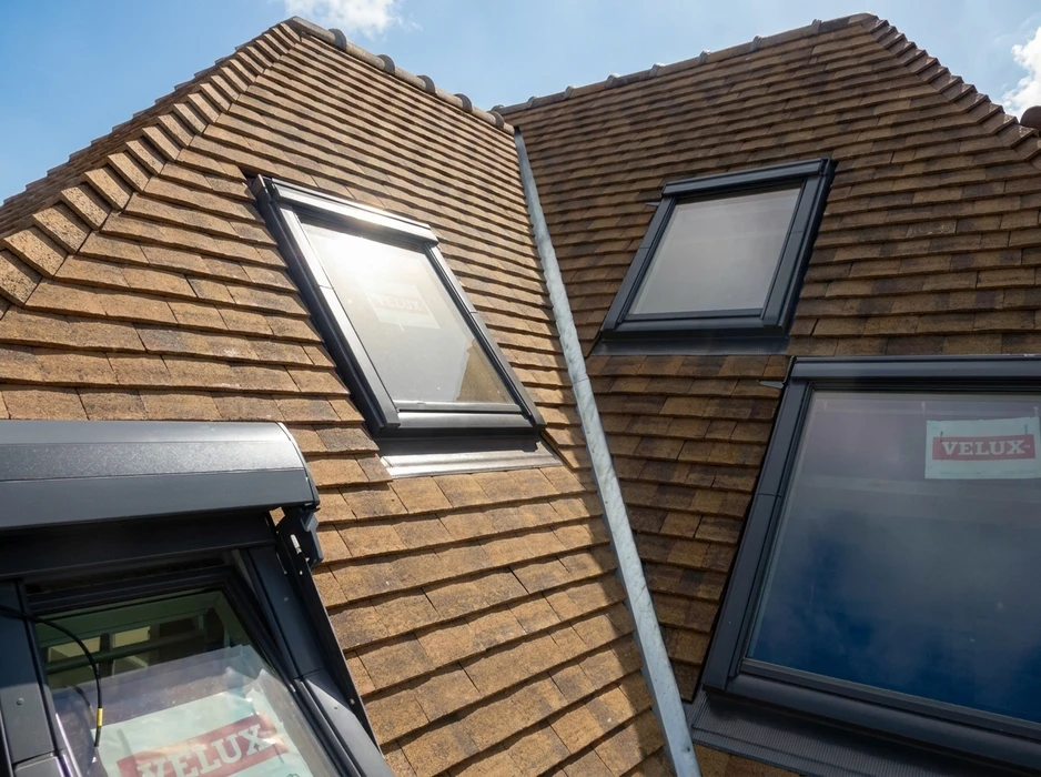 Toiture en tuiles plates de teinte brun-ocre avec plusieurs fenêtres de toit de marque VELUX à cadre anthracite