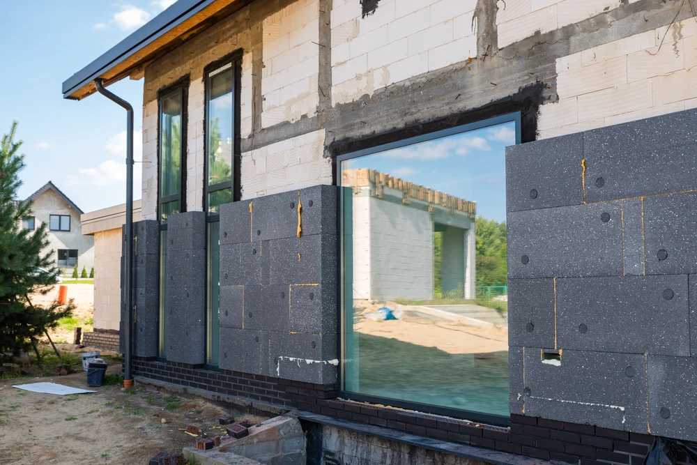 Ouvrier en bâtiment appliquant un enduit de façade extérieure depuis un échafaudage