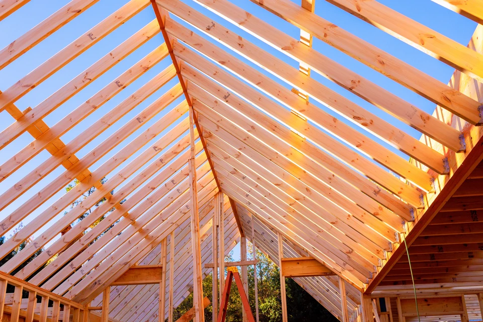 Ouvrier en combinaison de protection blanche et bonnet installant de l'isolation thermique jaune dans les combles d'une habitation