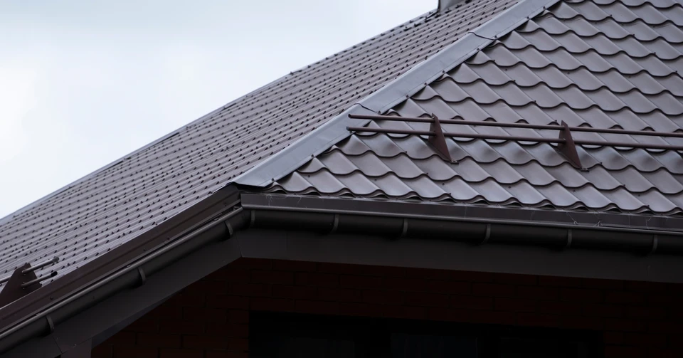 Ouvrier en combinaison de protection intégrale blanche avec masque respiratoire effectue des travaux de décontamination sur échafaudage extérieur d'un bâtiment résidentiel aux façades beiges et menuiseries vertes