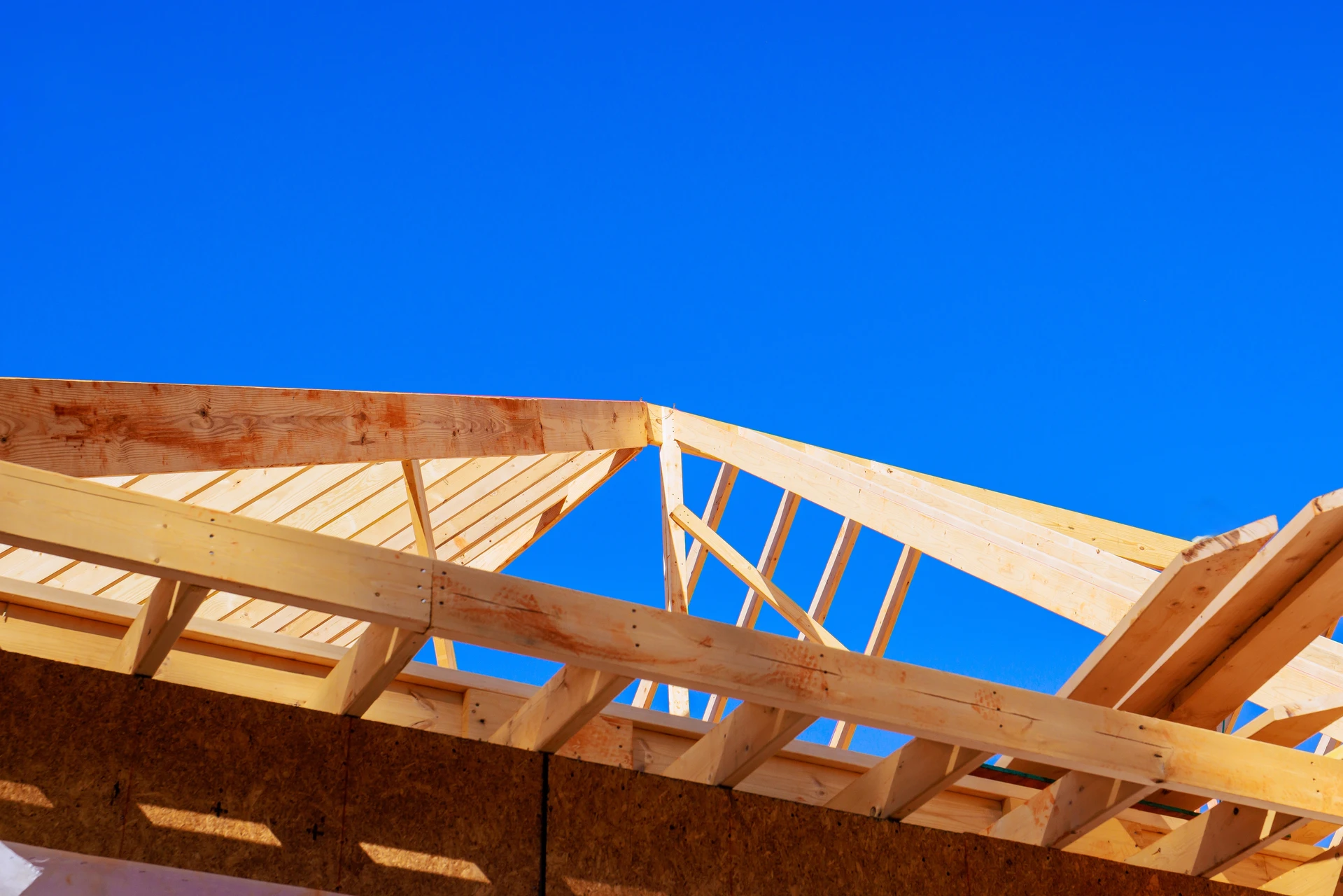 Chantier de construction résidentielle en cours avec charpente bois apparente et échafaudage métallique