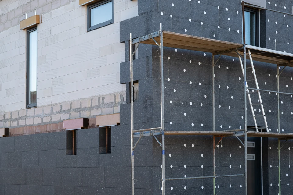Maison individuelle contemporaine avec façade crépie beige, toiture en tuiles mécaniques grises, cheminées maçonnées